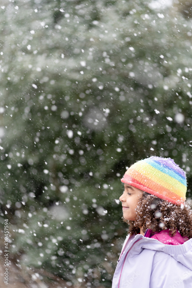 Profile of girl in rainbow cap standing in snow Profile of girl in rainbow cap standing in snow