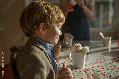 Boy grins at cup overflowing with whipped cream  photo