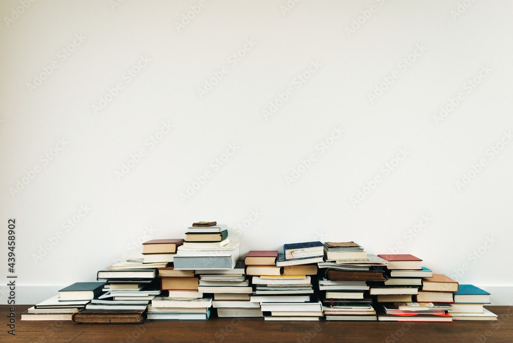 Stacked books against a white wall Stacked books against a white wall