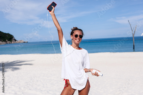 Cheerful woman listening to music on seashore photo