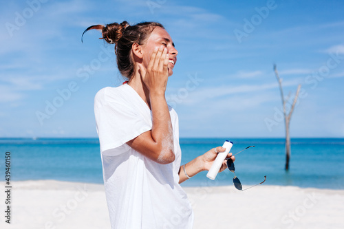 Sunburned Woman applying suntan lotion on beach