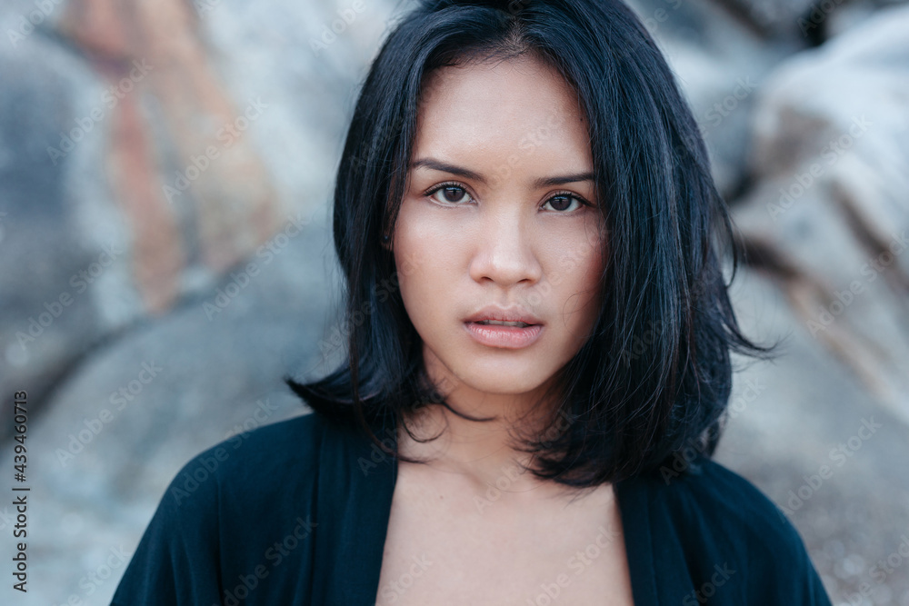 Asian woman closeup against cliff on seashore Asian woman closeup against cliff on seashore