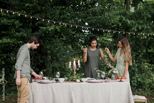 Friends Arranging Flowers and Setting Table  for Backyard Dinner photo