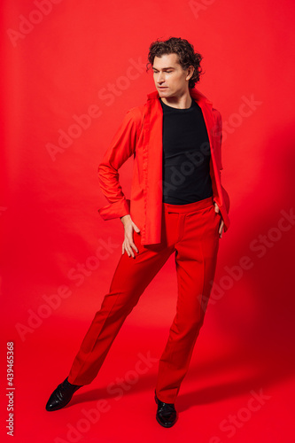 Tall handsome man dressed in red shirt posing on the red background © Smile