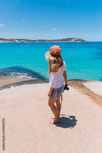 A blond woman exploring the cliffy coastline and bright blue ocean photo