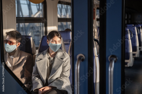 Passengers in masks sitting behind train door photo