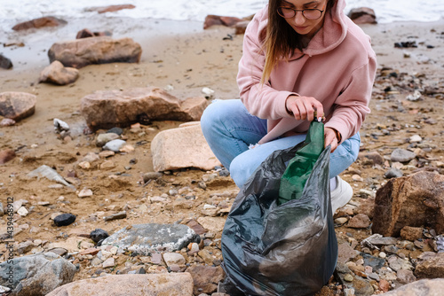 Young woman collecting litter near sea photo