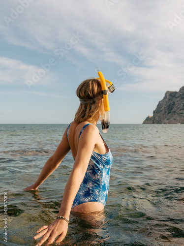 Unrecognizable female swimmer with snorkel standing in sea water photo