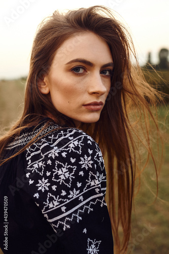 Close up fashion portrait of young beautiful woman dressed in navy blue embroidered shirt.