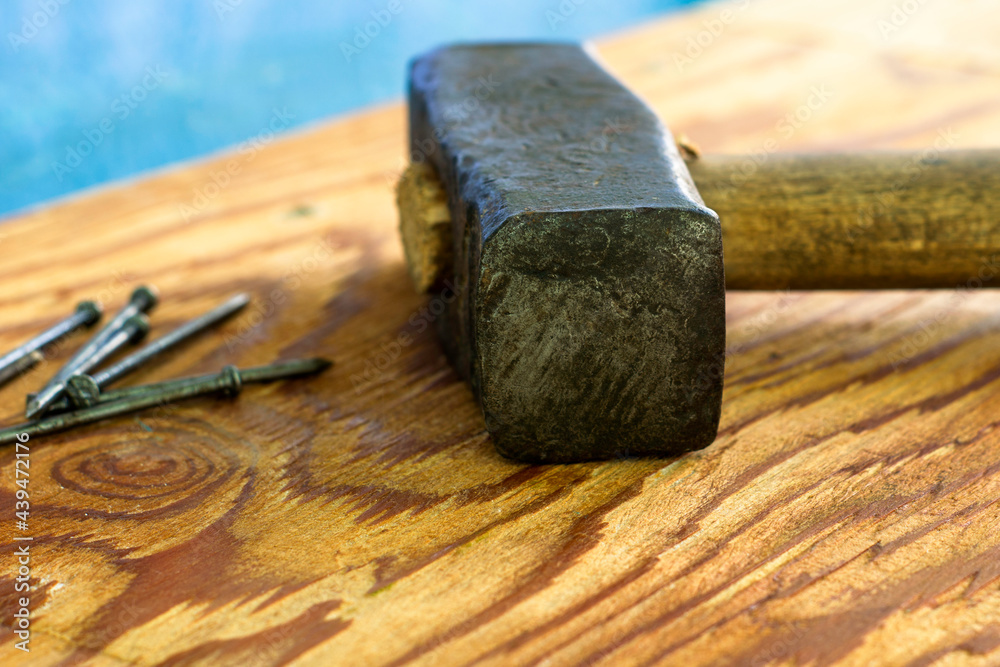 a large iron hammer and nails on a wooden surface