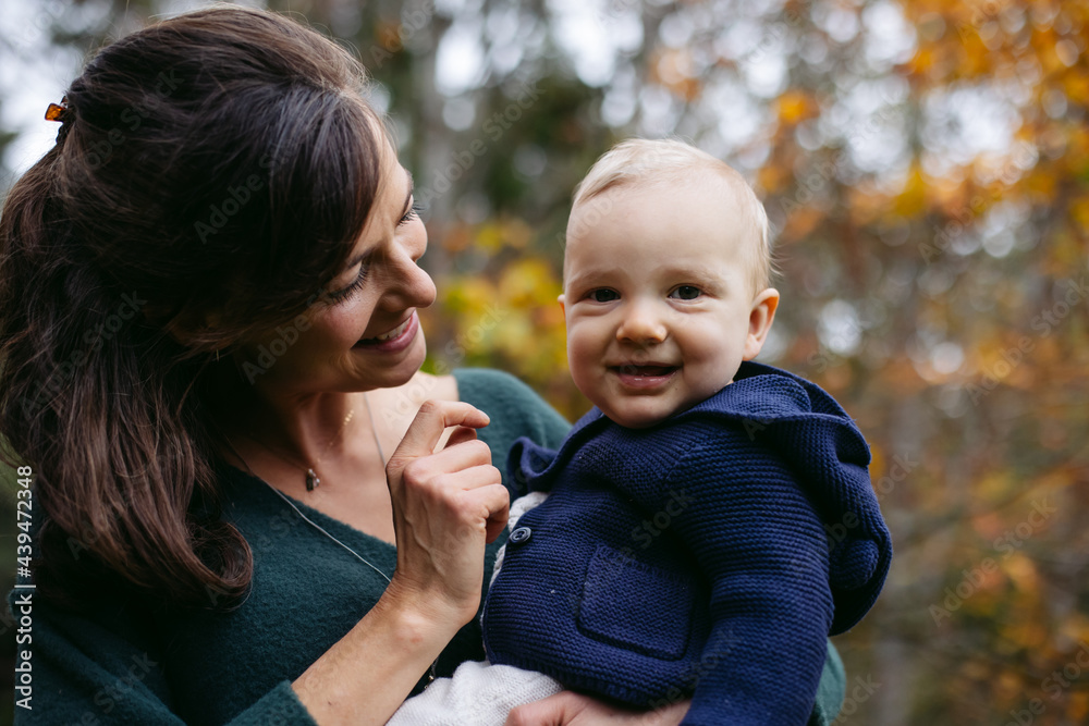 Loving mom holding and cuddling cute baby boy outside in the wal Loving mom holding and cuddling cute baby boy outside in the wal