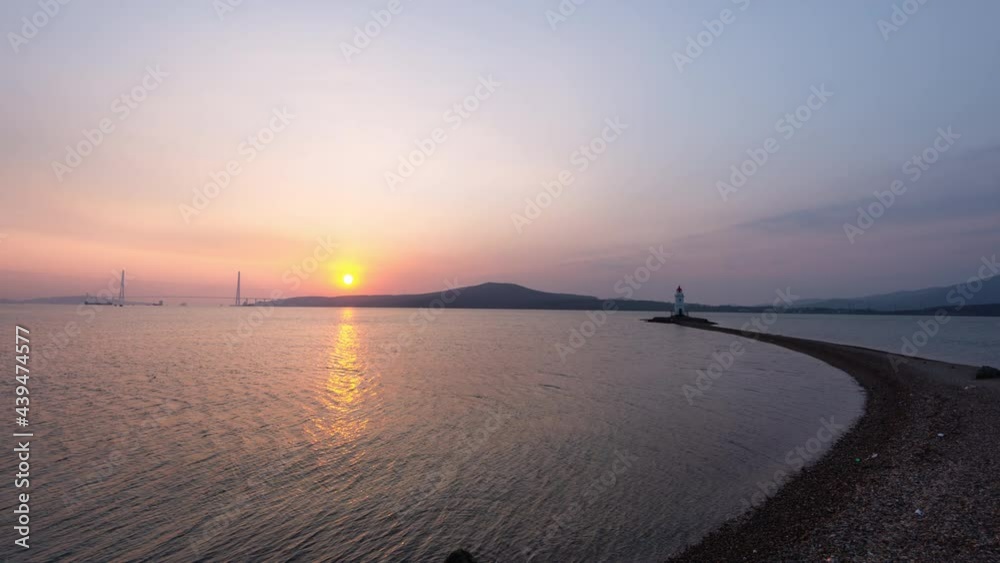 Timelapse of beautiful sunrise above the sea. Silhouette of the Russian bridge and Tokarevsky lighthouse in Vladivostok, Russia. Camera moves back Timelapse of beautiful sunrise above the sea. Silhouette of the Russian bridge and Tokarevsky lighthouse in Vladivostok, Russia. Camera moves back