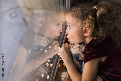 Girl on the windowsill with her favourite toy 
