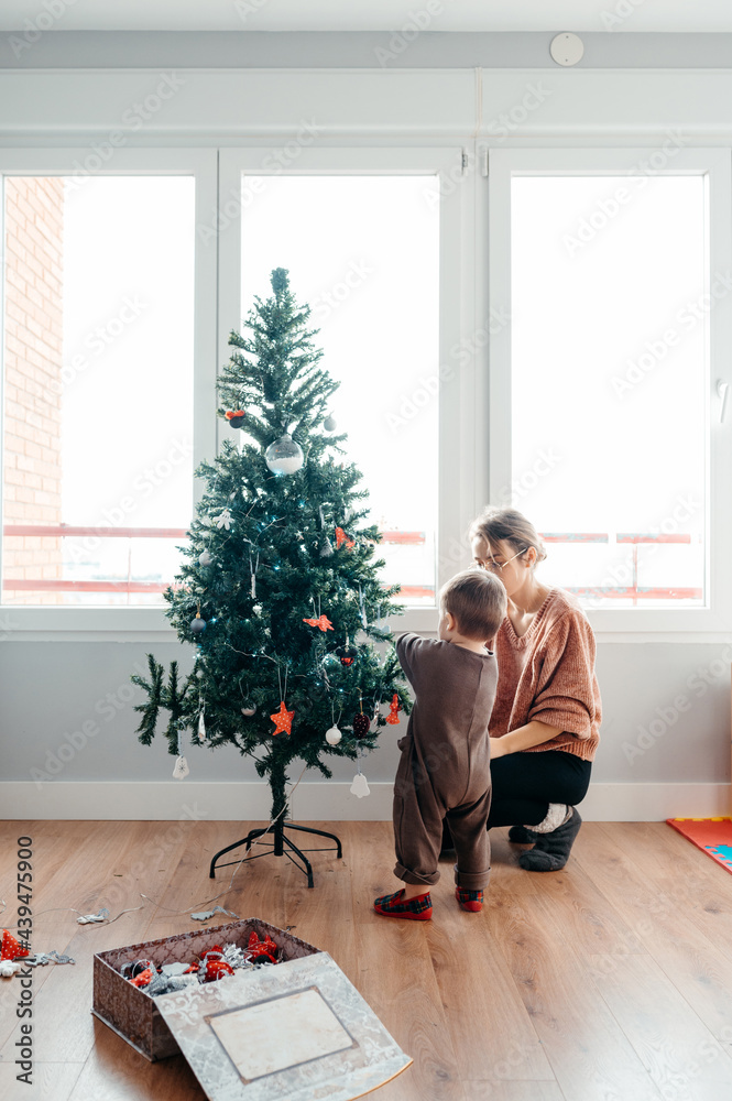 Toddler and mother decorating tree. Toddler and mother decorating tree.