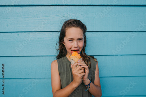 Child licks and enjoys an ice cream cone against a bright wall  photo
