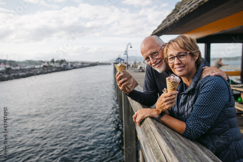 Elderly couple smiles and enjoys ice cream on a dock