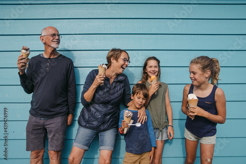 Grandparents and grandkids laugh and lean against a wall and enj photo
