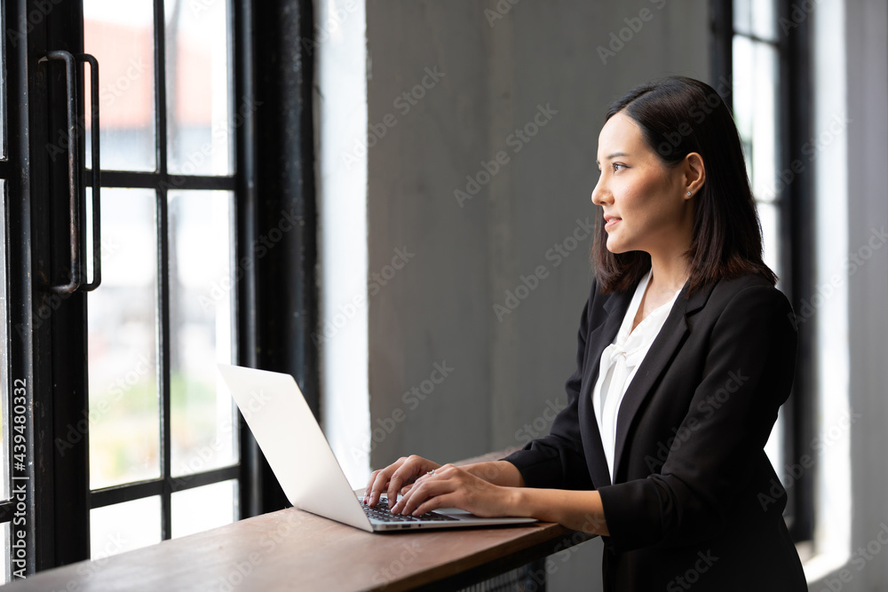 businesswoman working with laptop computer and looking at window in office businesswoman working with laptop computer and looking at window in office