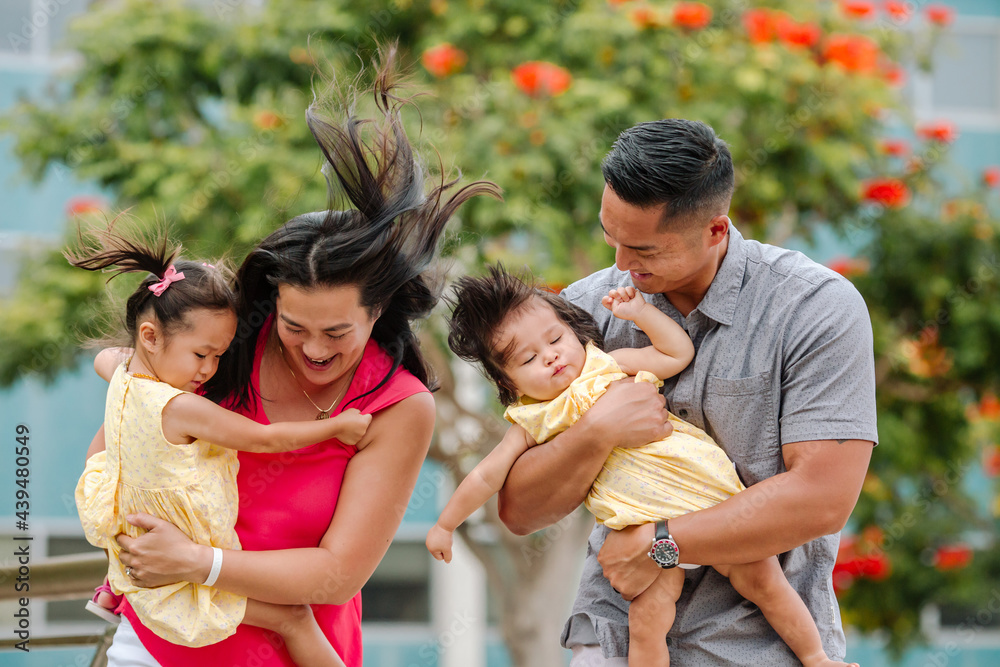 Air from sidewalk grate blows on laughing asian family Air from sidewalk grate blows on laughing asian family
