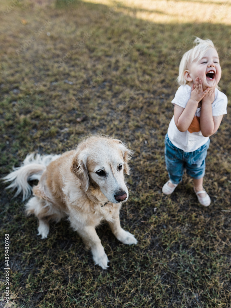 Little girl laughing with joy next to a dog Little girl laughing with joy next to a dog