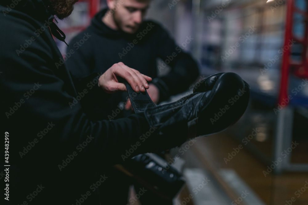 Pugilist taking off gloves after completing boxing match Pugilist taking off gloves after completing boxing match