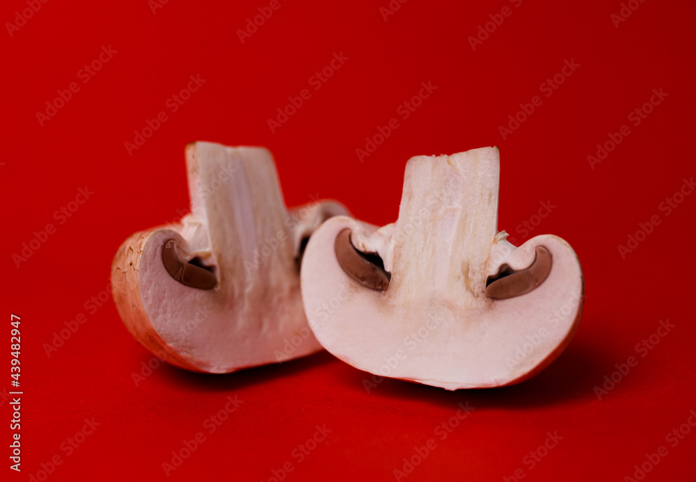 Fototapeta premium two mushrooms of mushrooms in a cut on a red background