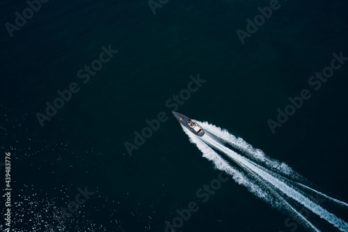 Motor performance boat in the sea. Drone view of a boat sailing. Top view of a white boat sailing to the blue sea. Large white boat fast movement on blue water aerial view. © Berg