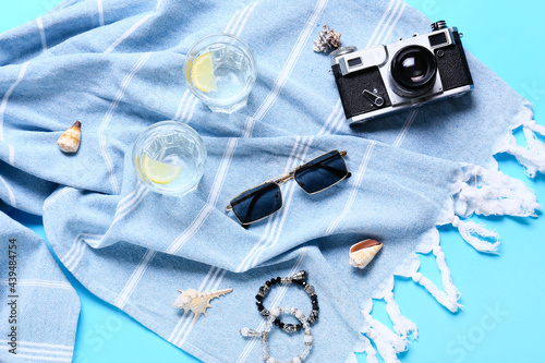 Stylish sunglasses with photo camera, glasses of water and scarf on color background