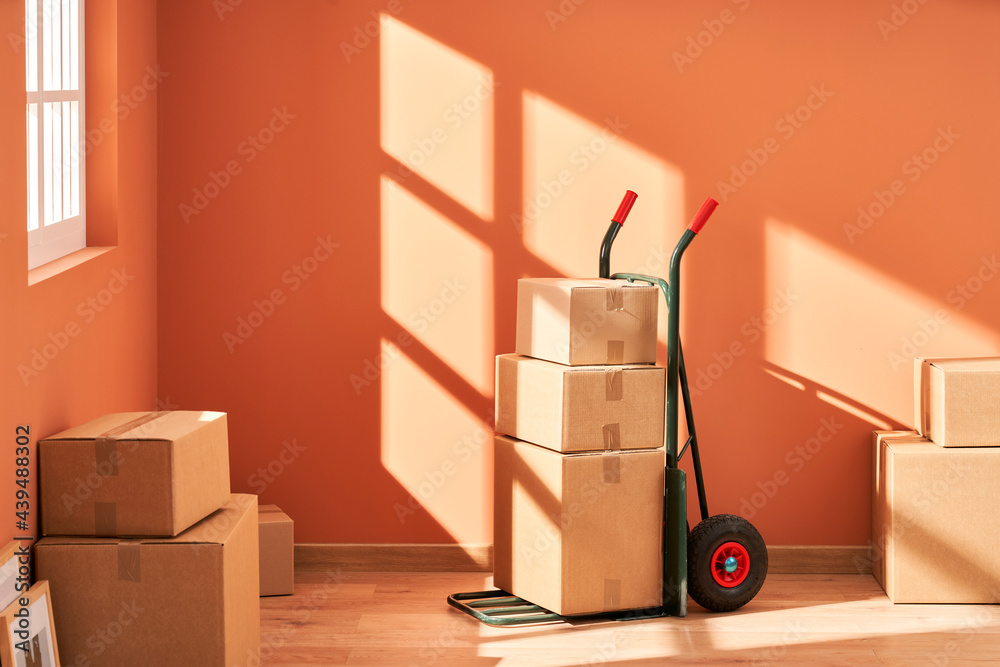 © Martí Sans/Stocksy - Trolley with packed boxes for relocation © Martí Sans/Stocksy - Trolley with packed boxes for relocation