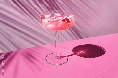 Pink champagne with ice on the table with sun shadows. Tropical concept.