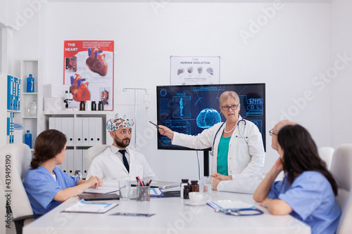 Hospital medical team doing brain activity research using headset with sensors monitoring radiography expertise. Physician doctors analyzing sickness treatment working in conference meeting room