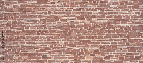 Wand aus vielen kleinen verschiedenen Steinen aus rotem Sandstein