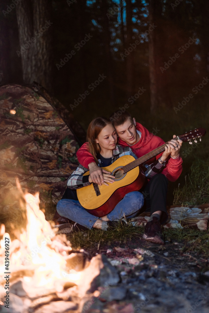 a happy couple in love, a guy and a girl together on a picnic near the campfire with a guitar. romantic weekend picnic