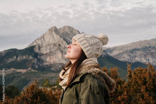 Young woman feeling relaxed in front of scenic mountain landcape photo