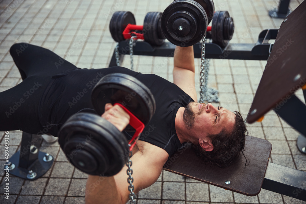 Kind bearded male person lifting heavy dumbbells Kind bearded male person lifting heavy dumbbells