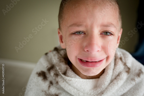 crying boy covered in hair clippings