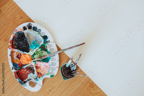 Paint palette with acrylic paints and paint brushes on the floor photo