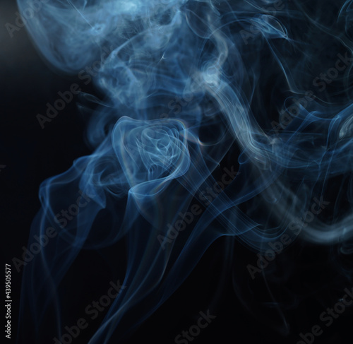 Flowing patterns of smoke from burning isolated black background.