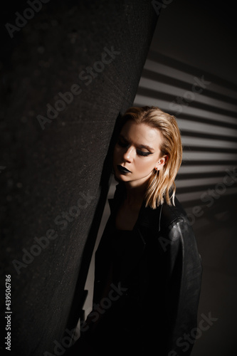 Beautiful girl with white hair in a black leather jacket on a black background