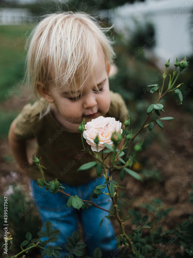 young blonde child smelling flowers