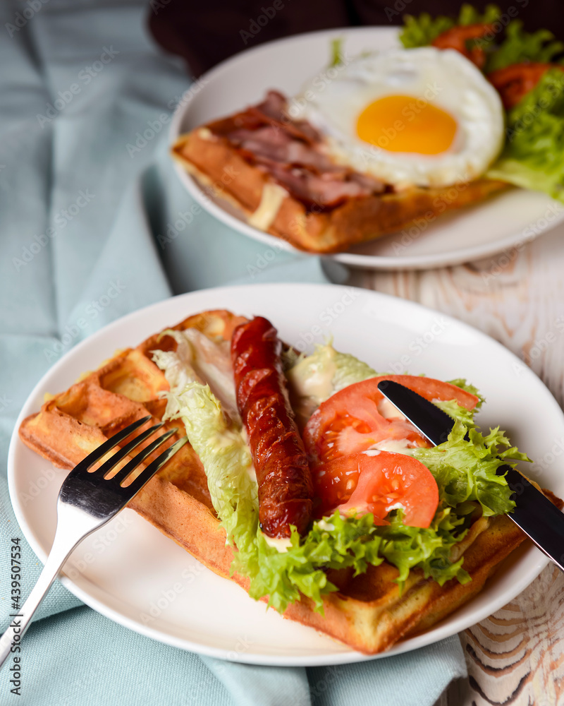Waffle wholesome breakfast. Sour waffles with grilled sausages, fried eggs, delicious sauce and fresh vegetables.