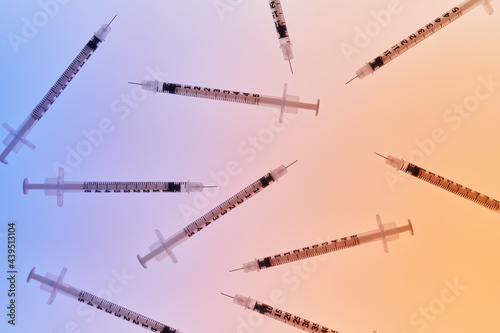 Grouping of Medical Syringes on Blue-Orange Background 