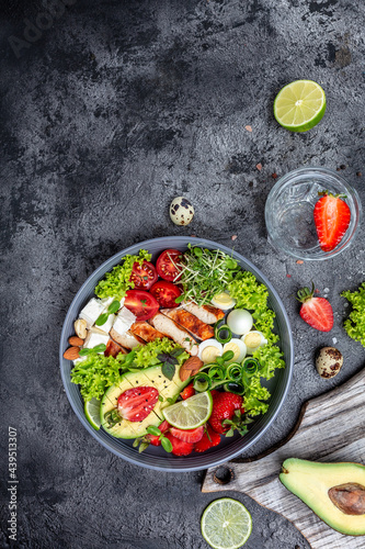 Ketogenic diet food, chicken fillet, quinoa, avocado, avocado, feta cheese, quail eggs, strawberries, nuts and lettuce. healthy meal concept, vertical image. top view. place for text