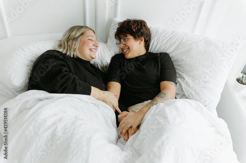 Married couple laying in bed together on phones photo