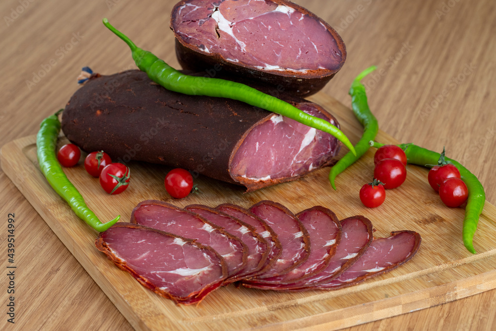 Turkish pastrami on a wooden serving plate. Whole and sliced pastrami. pastrami is made from the