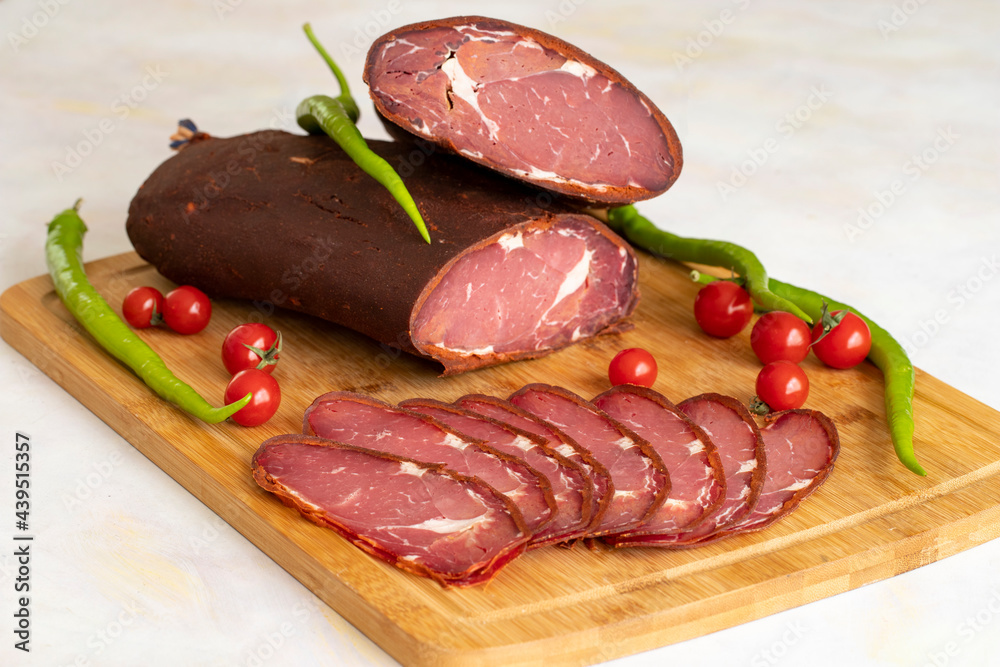 Turkish pastrami on a white background. Whole and sliced pastrami