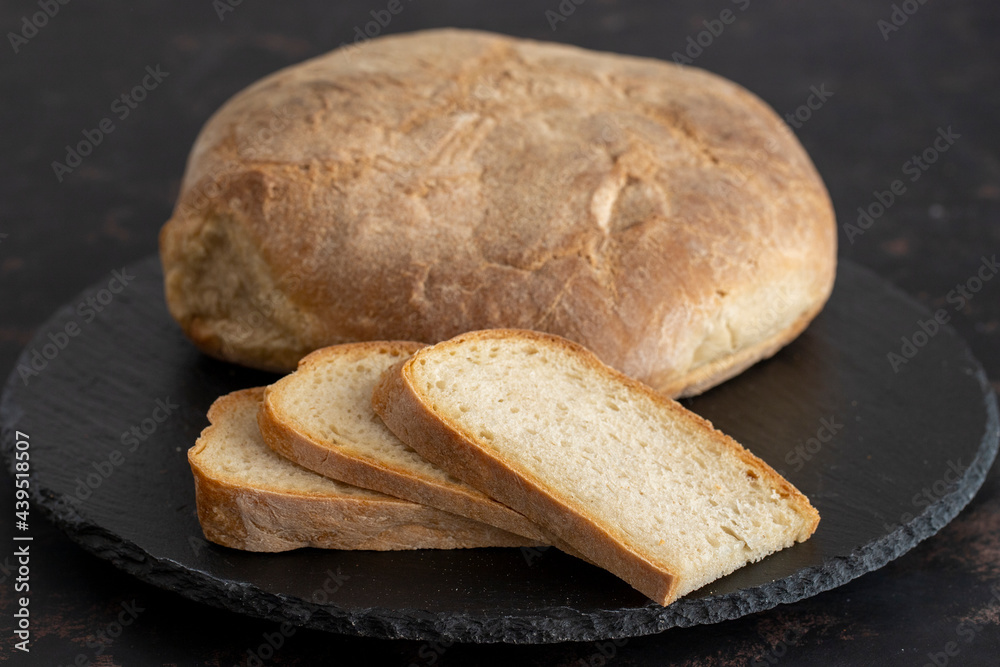 Organic round bread on a dark wooden background. Sliced bread. Traditional sourdough bread Organic round bread on a dark wooden background. Sliced bread. Traditional sourdough bread