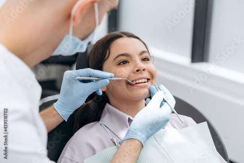 Portrait of a dentist doctor working with a patient teenager