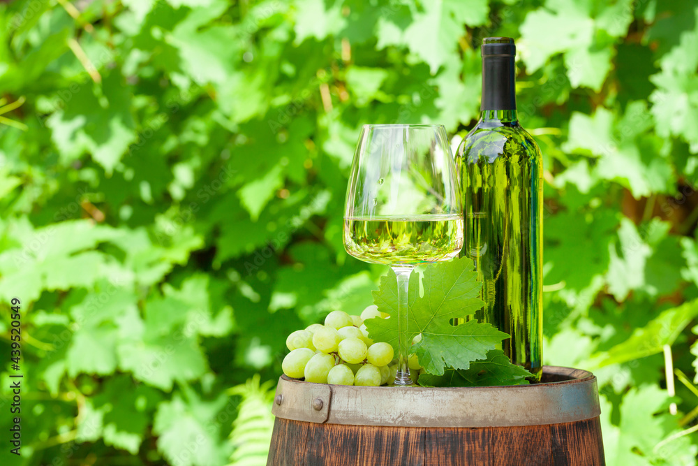Wine bottle, glass and grape on old wine barrel