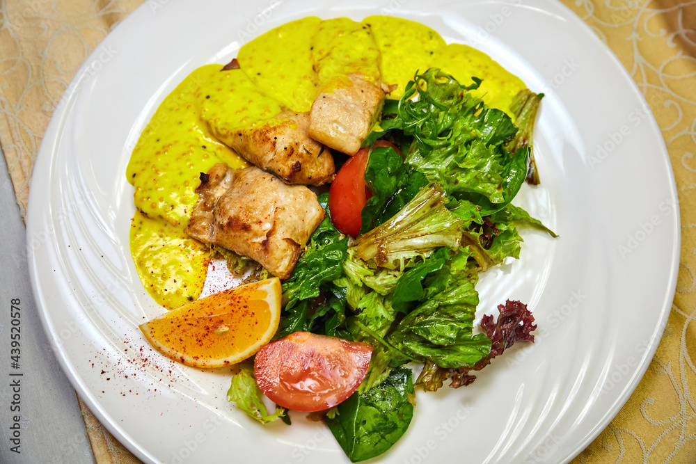 Baked pelengas fillet with salad mix with mustard-cream sauce. Close-up, selective focus